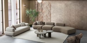 Set canapea modulară YAKAMOZ cu module în nuanțe de gri deschis, element curbat maro și fotoliu berjer cu model geometric.